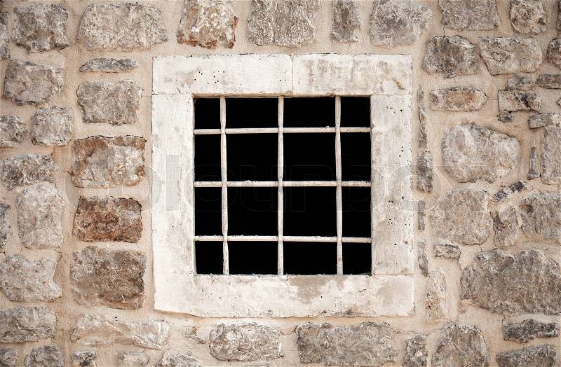Ancient stone prison wall with metal window bars, stock photo
