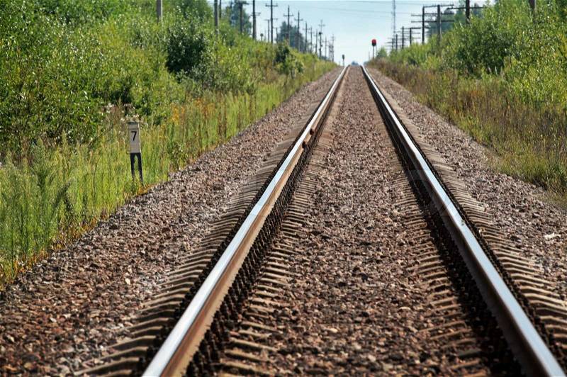 Straight modern railway perspective with gravel, poles, green grass and trees, stock photo