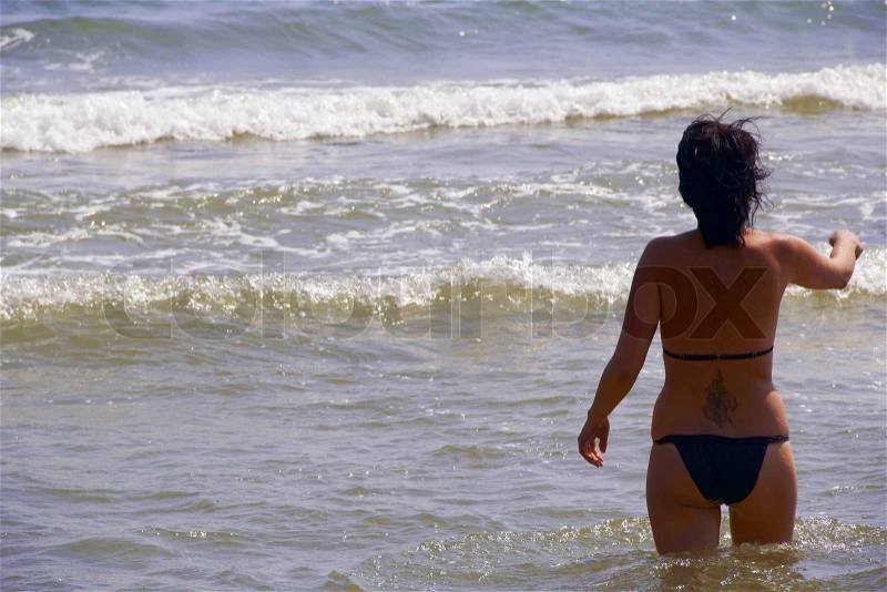 Girl or women with tattoo on back in sea, stock photo