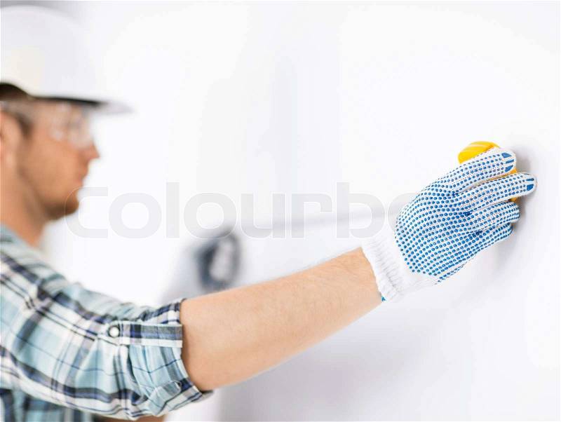 Architecture and home renovation concept - male architect measuring wall with flexible ruler, stock photo