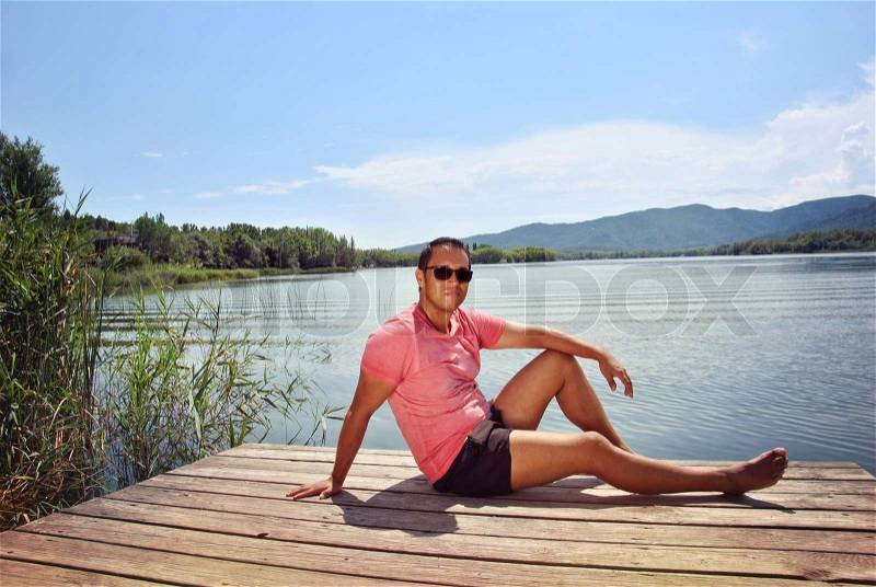 Man lying on the platform of a lake, stock photo