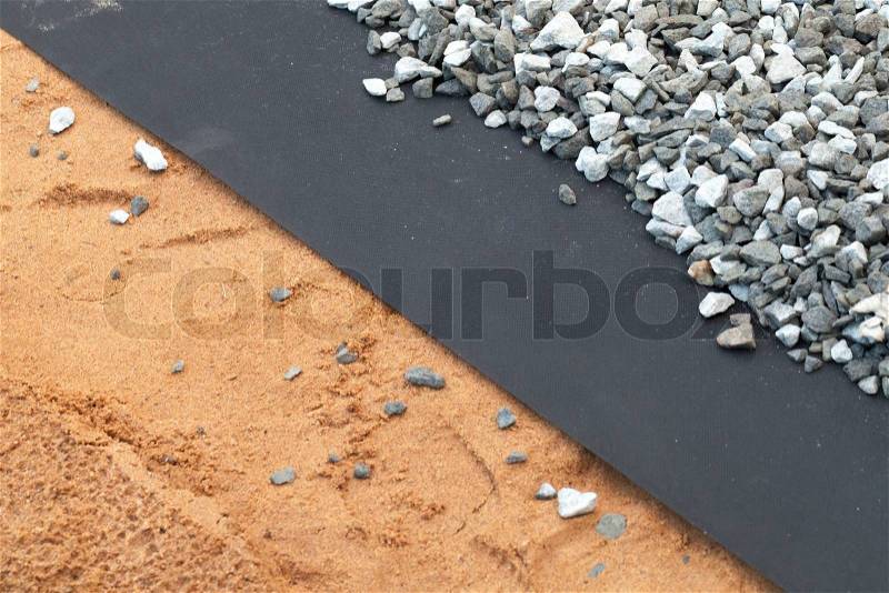 Geotextile layer between gray gravel and sandy ground, stock photo