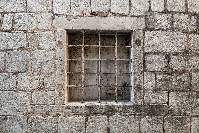 Locked ancient stone prison wall with metal window bars, stock photo