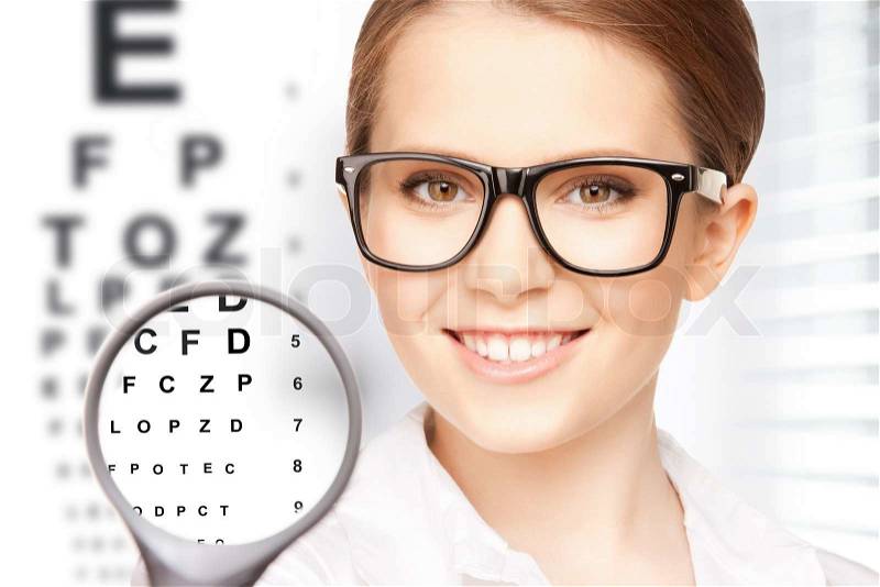 Medicine and vision concept - woman with magnifier and eye chart, stock photo