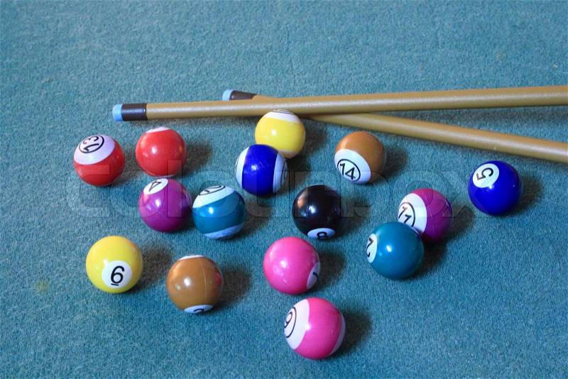 Pool balls on blue cloth in disorder with cues, stock photo
