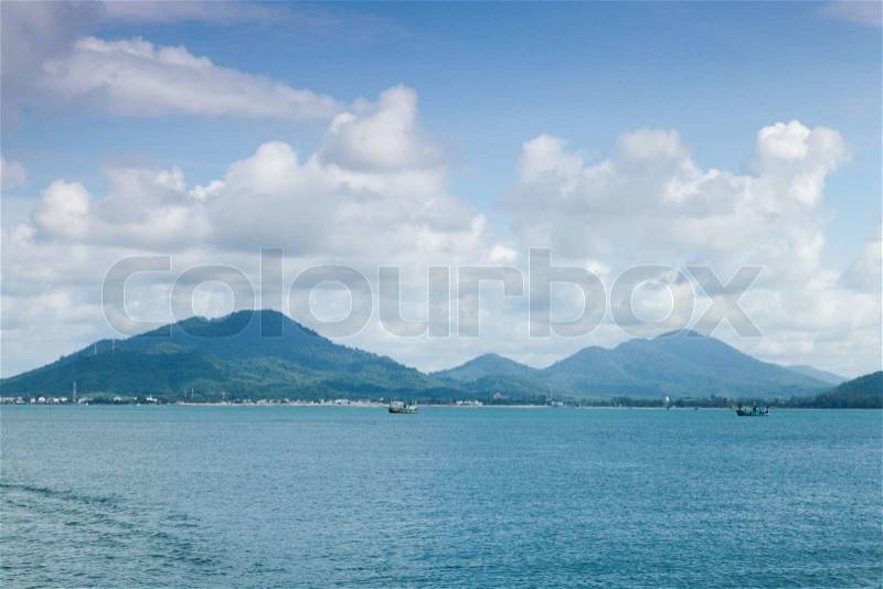 Mountains, sea and sky on a clear day atmosphere. A small boat sailing in the sea, stock photo