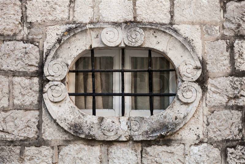 Ancient stone wall with metal window bars. Perast town, Montenegro, stock photo