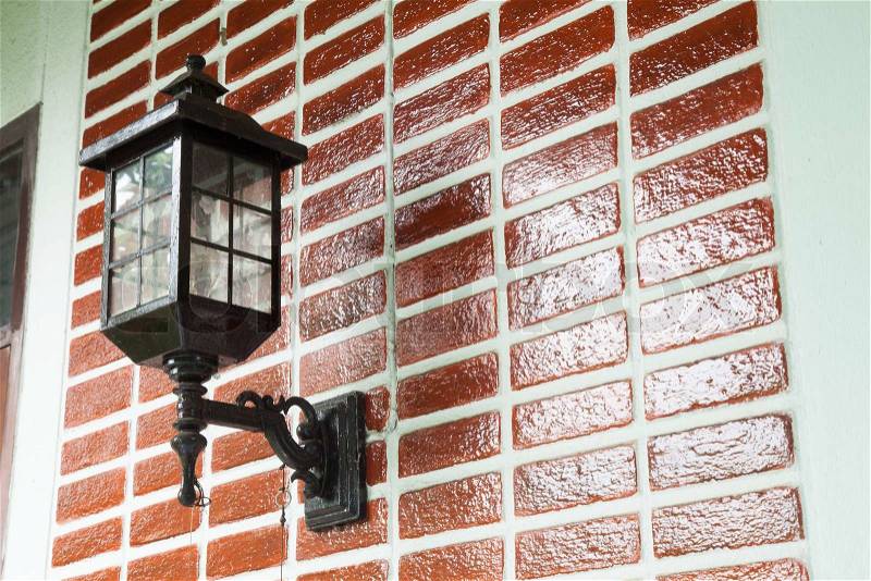 Lamp on the wall. Home painted red brick wall with black lamp, stock photo