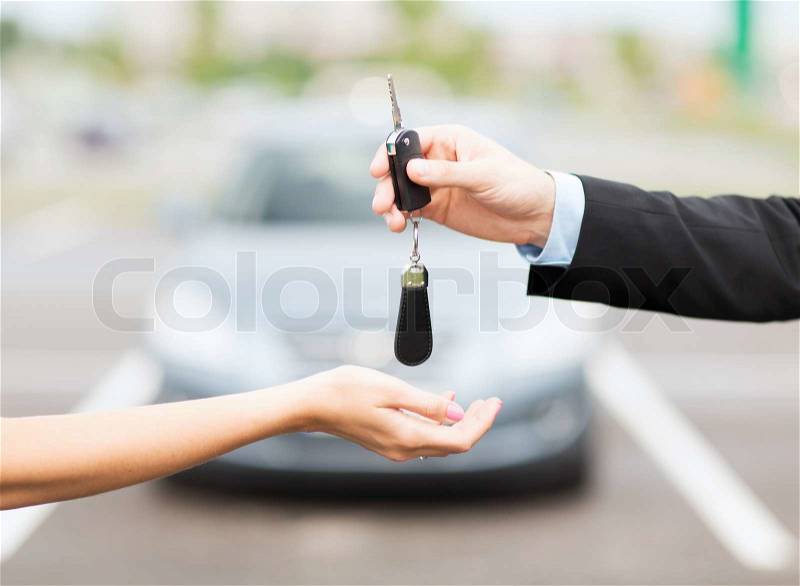 Transportation and ownership concept - customer and salesman with car key outside, stock photo