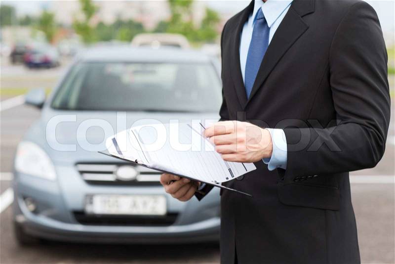 Transportation and ownership concept - man with car documents outside, stock photo