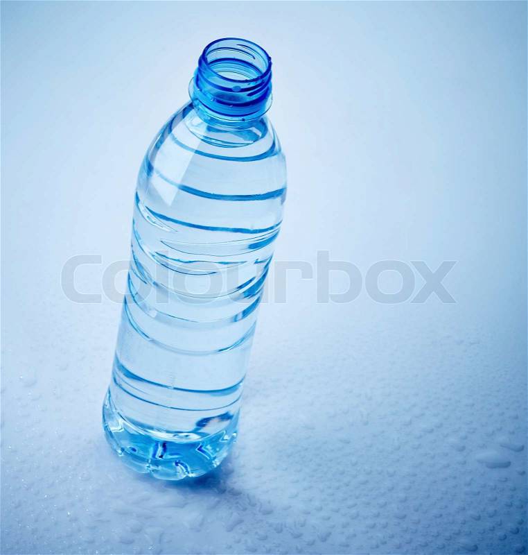 Plastic water bottle on wet blue background, stock photo