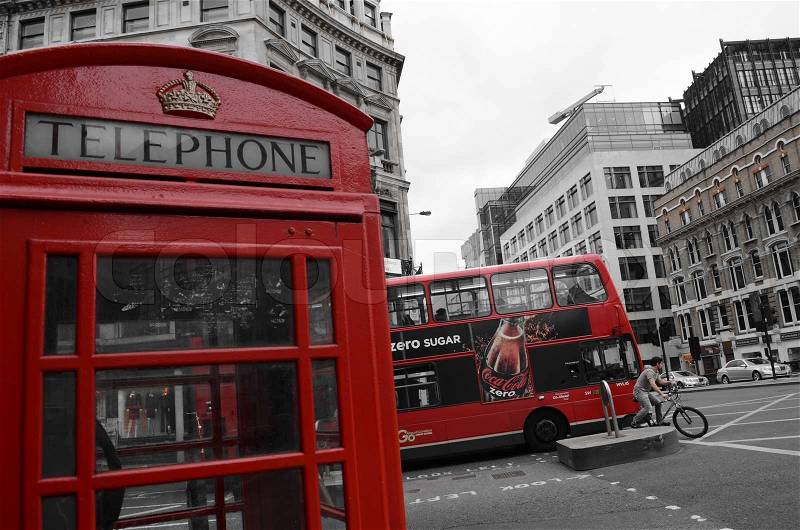 A red phonebooth in front of a red London bus in black and white street, stock photo