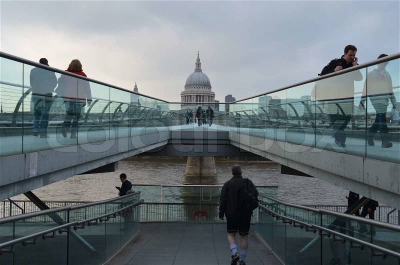 People walking on the pedestrian bridge Millenium Bridge in central London, with Saint Paul\'s cathedral in the horizon, stock photo