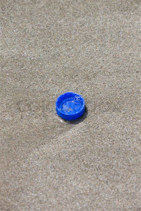 Blue plastic bottle cap on the beach, stock photo