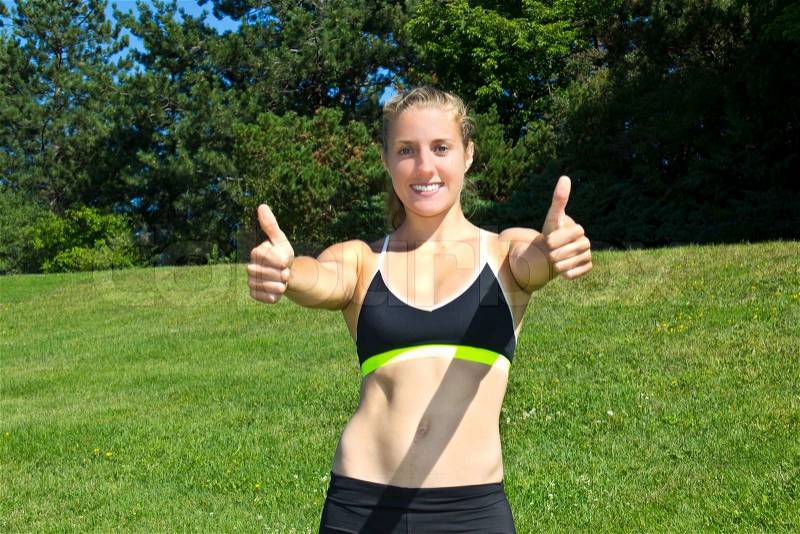 Fit, athletic woman giving thumbs up sign, stock photo