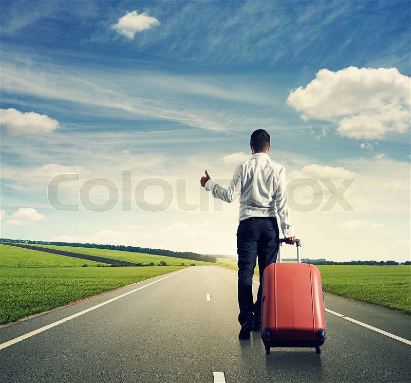 Back view of businessman hitch hiking on the road, stock photo