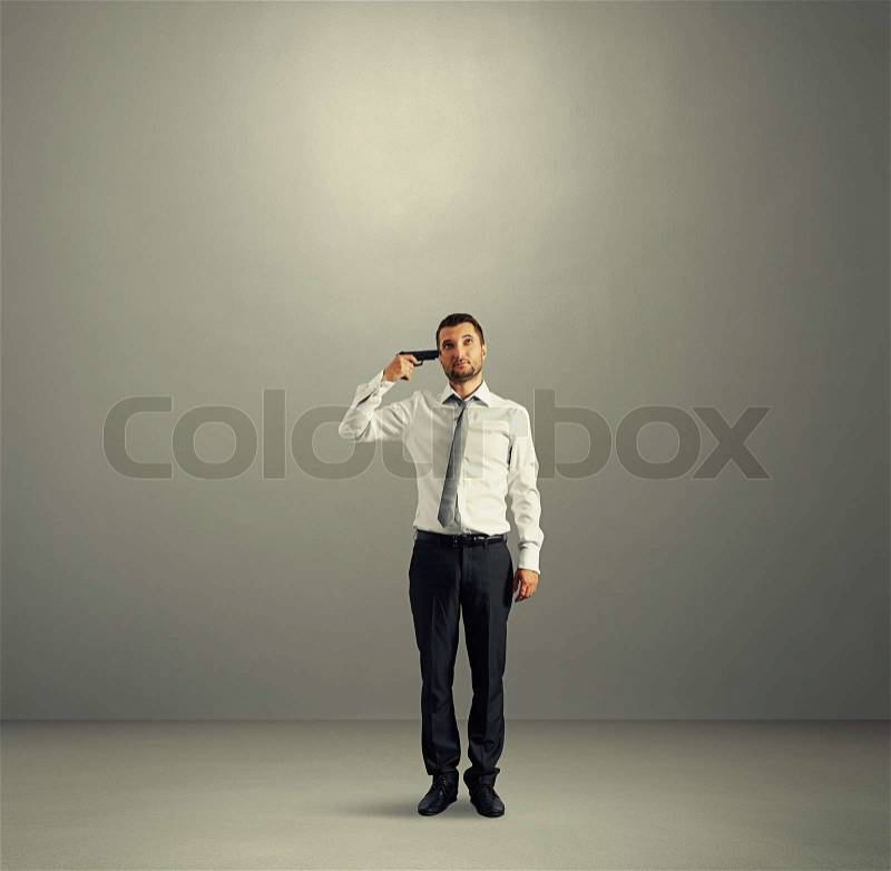 Full length shot of quiet businessman with gun in dark room, stock photo