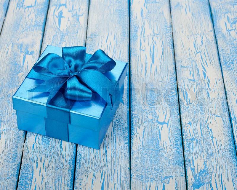 Box decorated with ribbon on blue background, stock photo