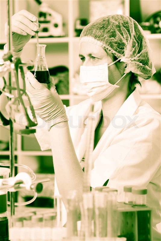 Scientific researcher holding at a liquid solution in a lab, stock photo