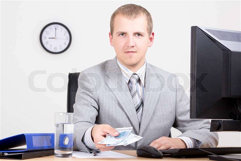 Young business man giving money in bright office, stock photo