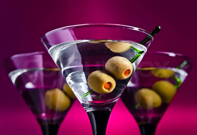 Glasses with martini and green olives, focus on olives, stock photo