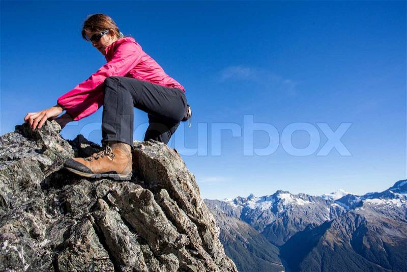 Youg woman climbing mountain ridge above the valley, stock photo
