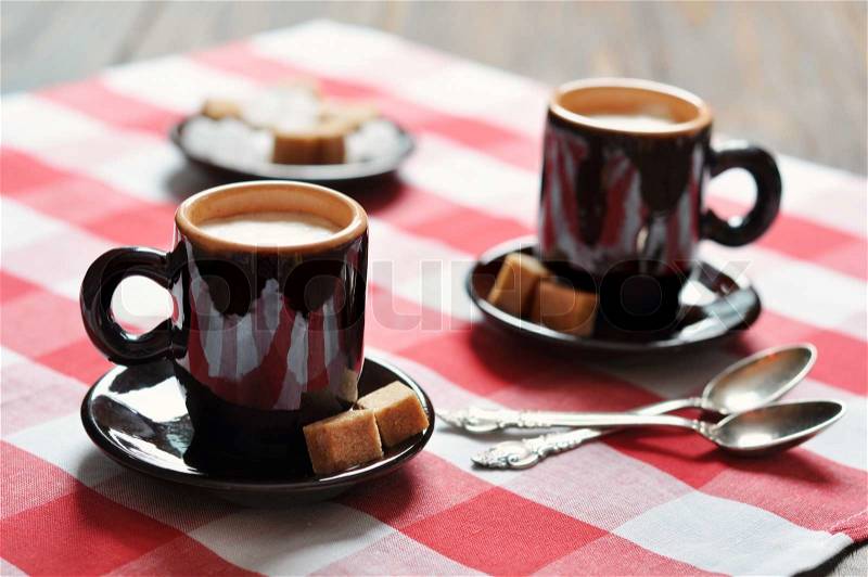 Two cups of espresso in brown cups on checkered napkin, stock photo