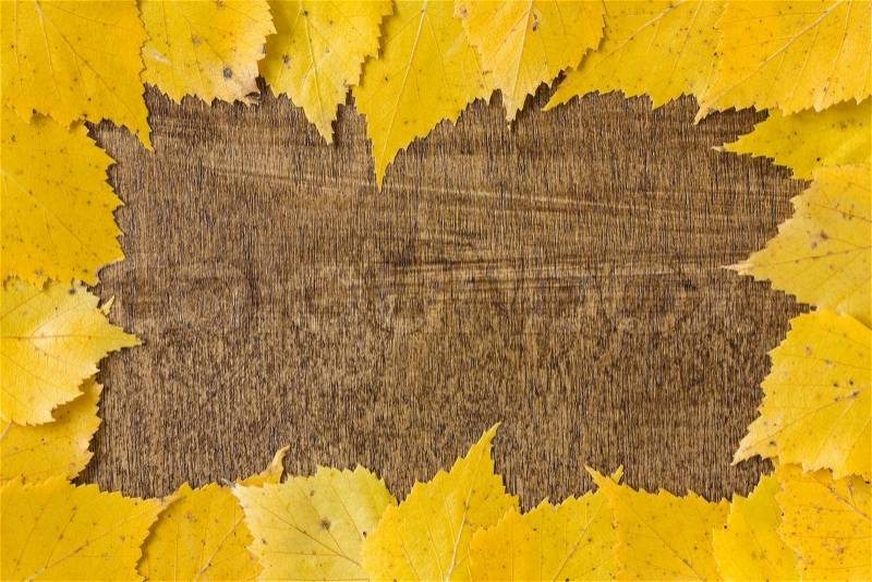 Autumn border from fallen leaves on wooden table, stock photo