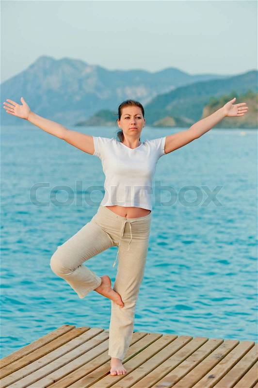 Girl standing on one leg with arms outstretched to the sides, stock photo