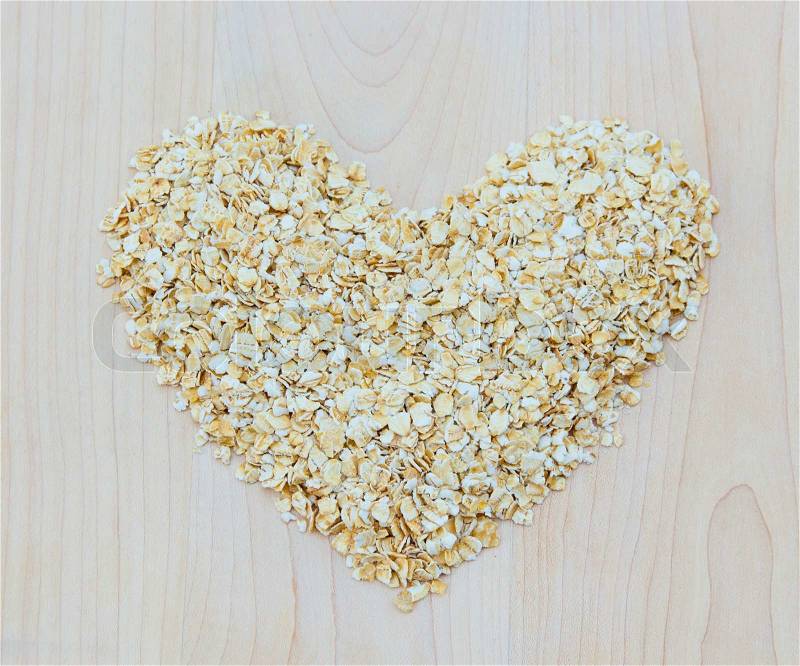 Whole grain oats in heart shape on wooden board, healthy food, stock photo