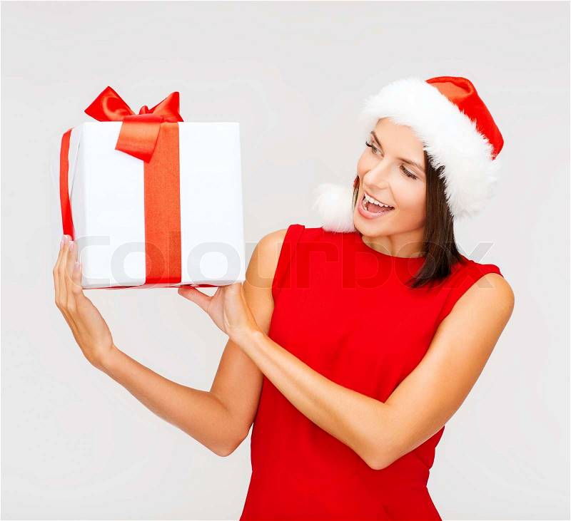 Christmas, x-mas, winter, happiness concept - smiling woman in santa helper hat with gift box, stock photo