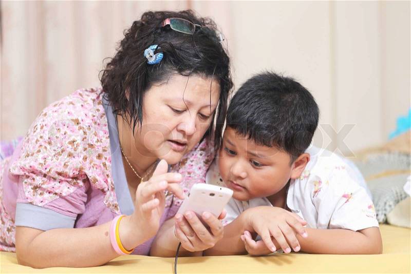 Asian mother and son. Playing smart phones, stock photo