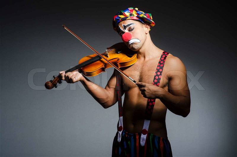 Sad clown performing at vioin, stock photo