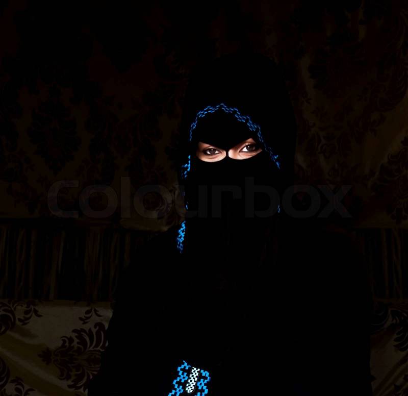 A Bedouin lady conceals her true beauty behind a black veil which is one of their rich tradition as Muslim where they only reveal their attractive eyes and ornate hands to the public or sometimes none at all, stock photo