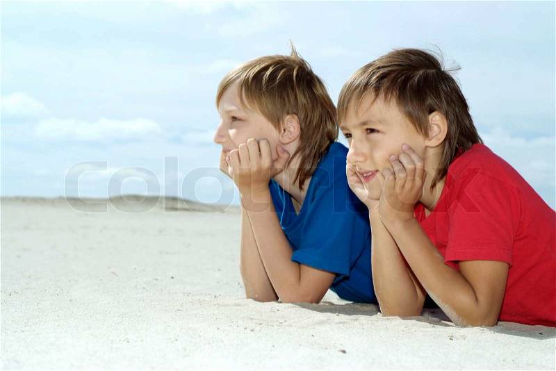 Beautiful children lie on the sand in the summer, stock photo
