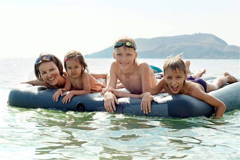 Portrait of a happy family swimming on an air mattress, stock photo