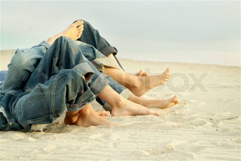 Feet four persons lying on the sand, stock photo