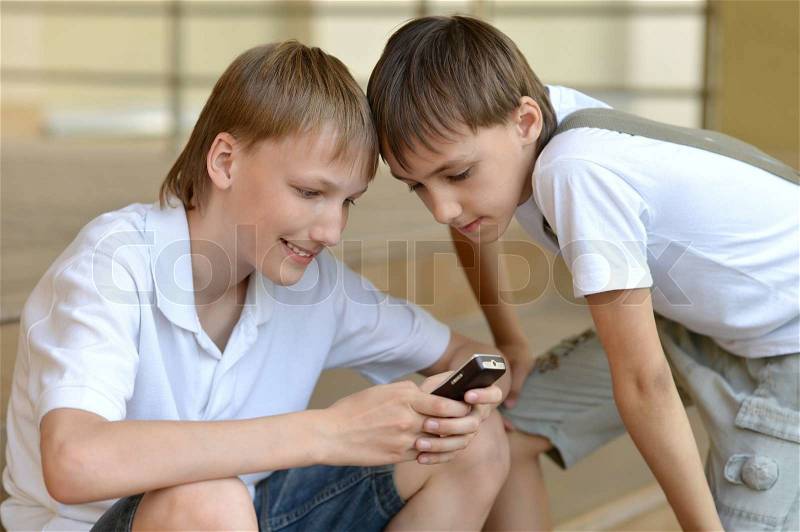 Two young guy playing the telephone game outdoors, stock photo