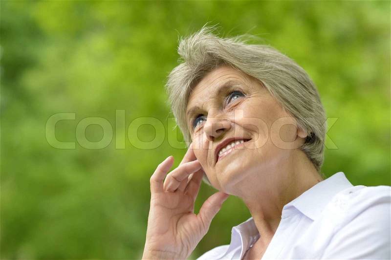 Portrait of an aged woman on a walk in the park in late spring, stock photo