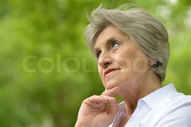 Portrait of an aged woman on a walk in the park in late spring, stock photo