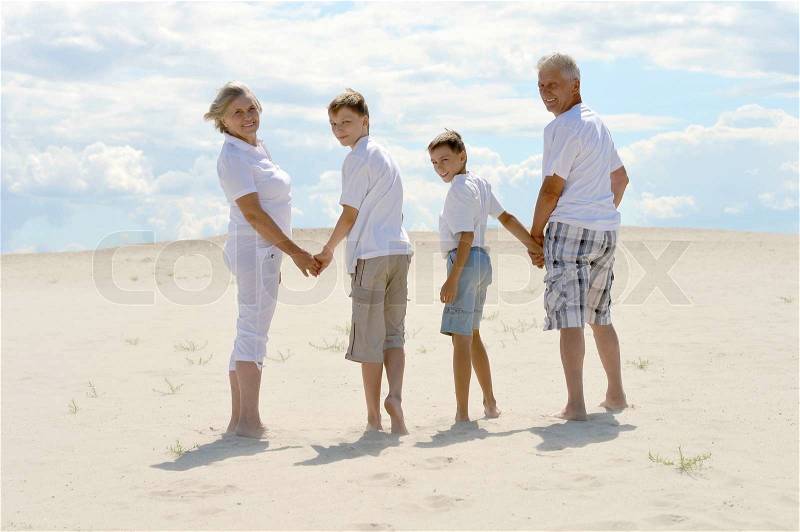 Funny brothers with their grandparents walking on the sand in the summer, stock photo