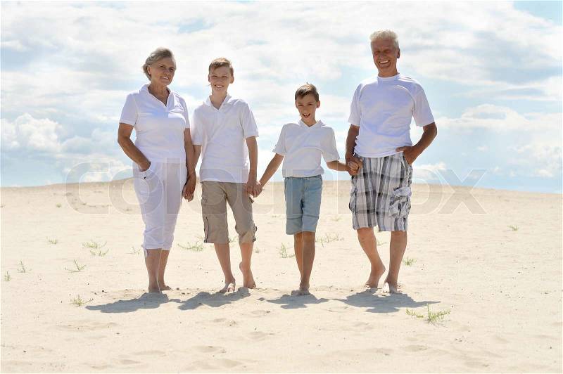 Funny brothers with their grandparents walking on the sand in the summer, stock photo