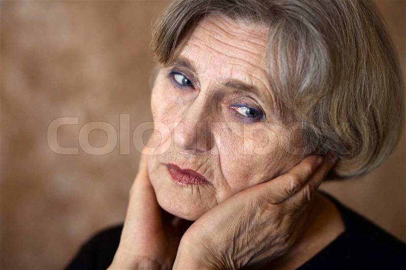 Close-up portrait of a sad older woman on a beige background, stock photo