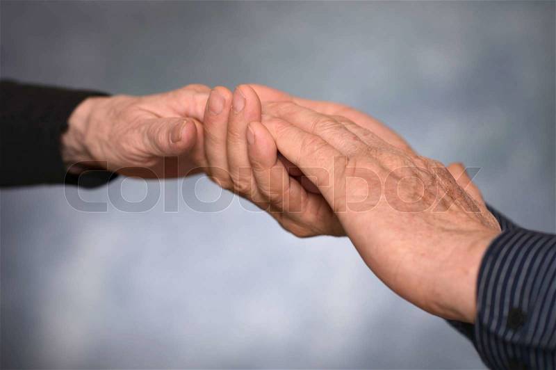 Concept shoot of friendship and love of man and woman: two hands over gray background, stock photo