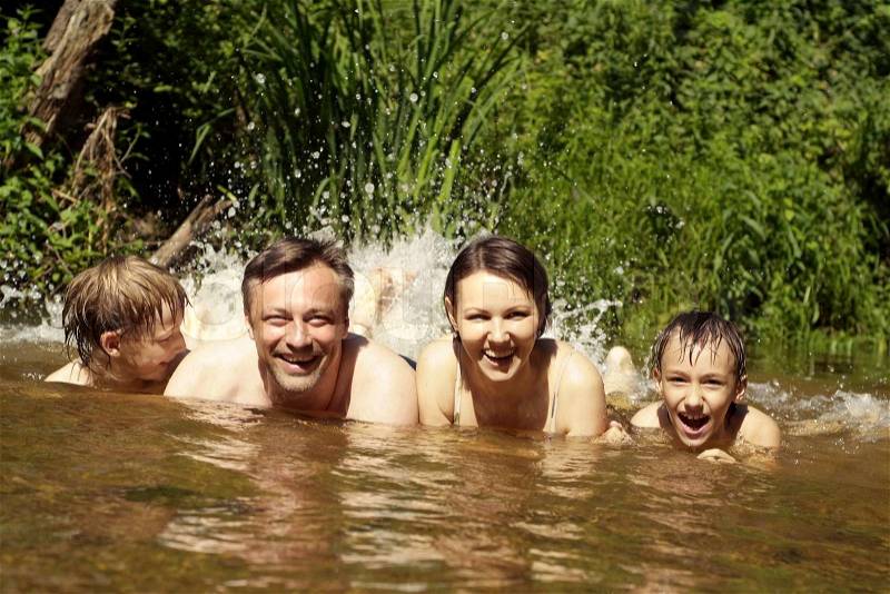 Happy family of four spends time outdoors in the summer, stock photo