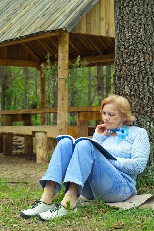 Older woman reading a magazine in the open air, stock photo