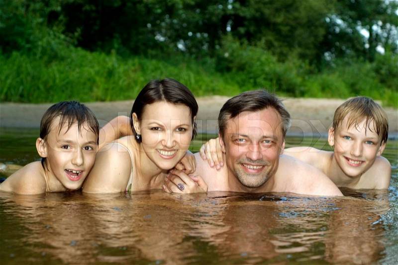 Beautiful family swims in the river in summer, stock photo