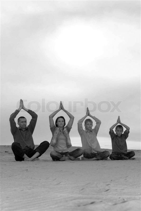 Happy Family four people meditating on the sand, stock photo