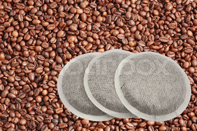 Coffee pads isolated over coffee beans background with clipping-path included, stock photo