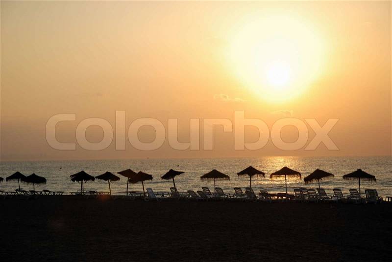 Dramatic sunrise on a mediterranean beach, sun glow reflecting on the sea surface, stock photo
